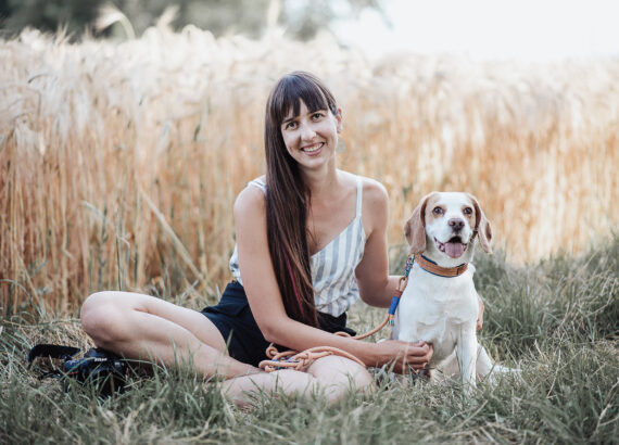 Junge Frau mit Hund in der Natur sitzend